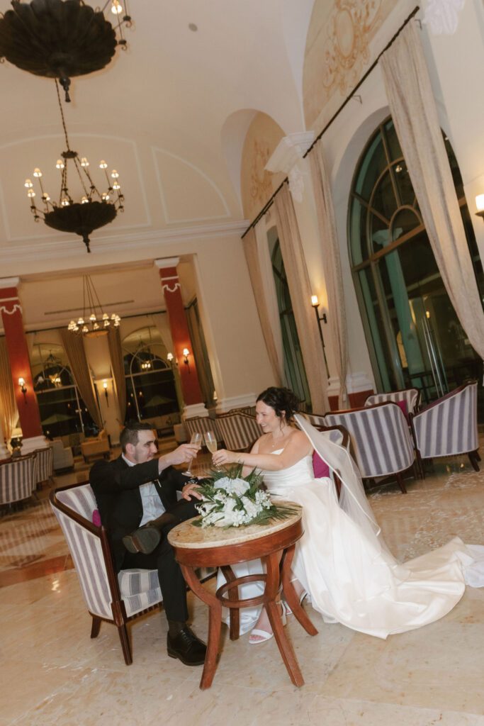 Close-up of couple’s hands clinking glasses during nighttime reception.