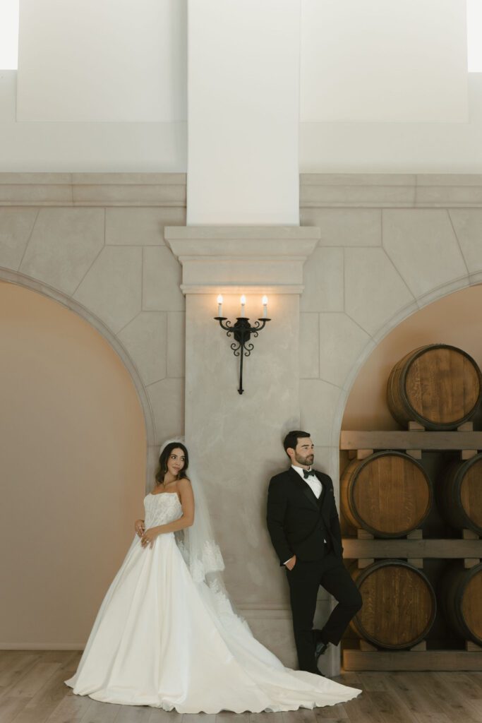 Intimate editorial pose of couple leaning against wine barrels at Monserate Winery