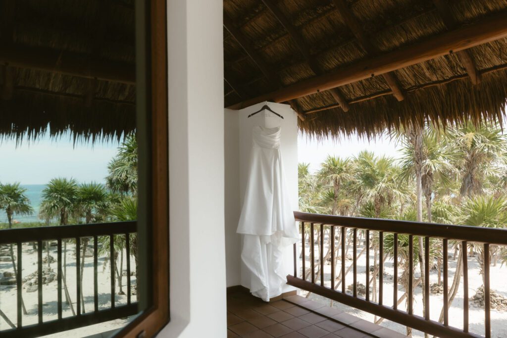 Wedding dress hanging in front of the balcony with tropical breeze coming through.